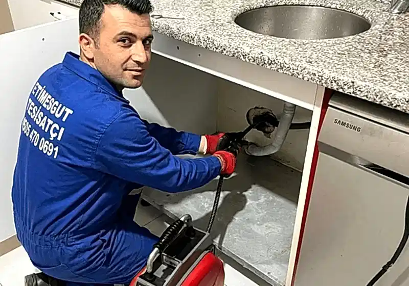 Etimesgut Tesisatçı Ada Tesisat üniformalı usta mutfak lavabosu altındaki tıkanıklığı robot makine ile açarken